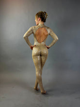 A woman in a Champagne Fairy Sequin Catsuit with an open back and turtleneck stands in a studio with a gray backdrop, the sparkly performance costume&