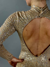A person wearing the Champagne Fairy Sequin Catsuit—featuring a turtleneck, sleeves, and an open back—sparkles against a gray background, evoking glamorous performance style.
