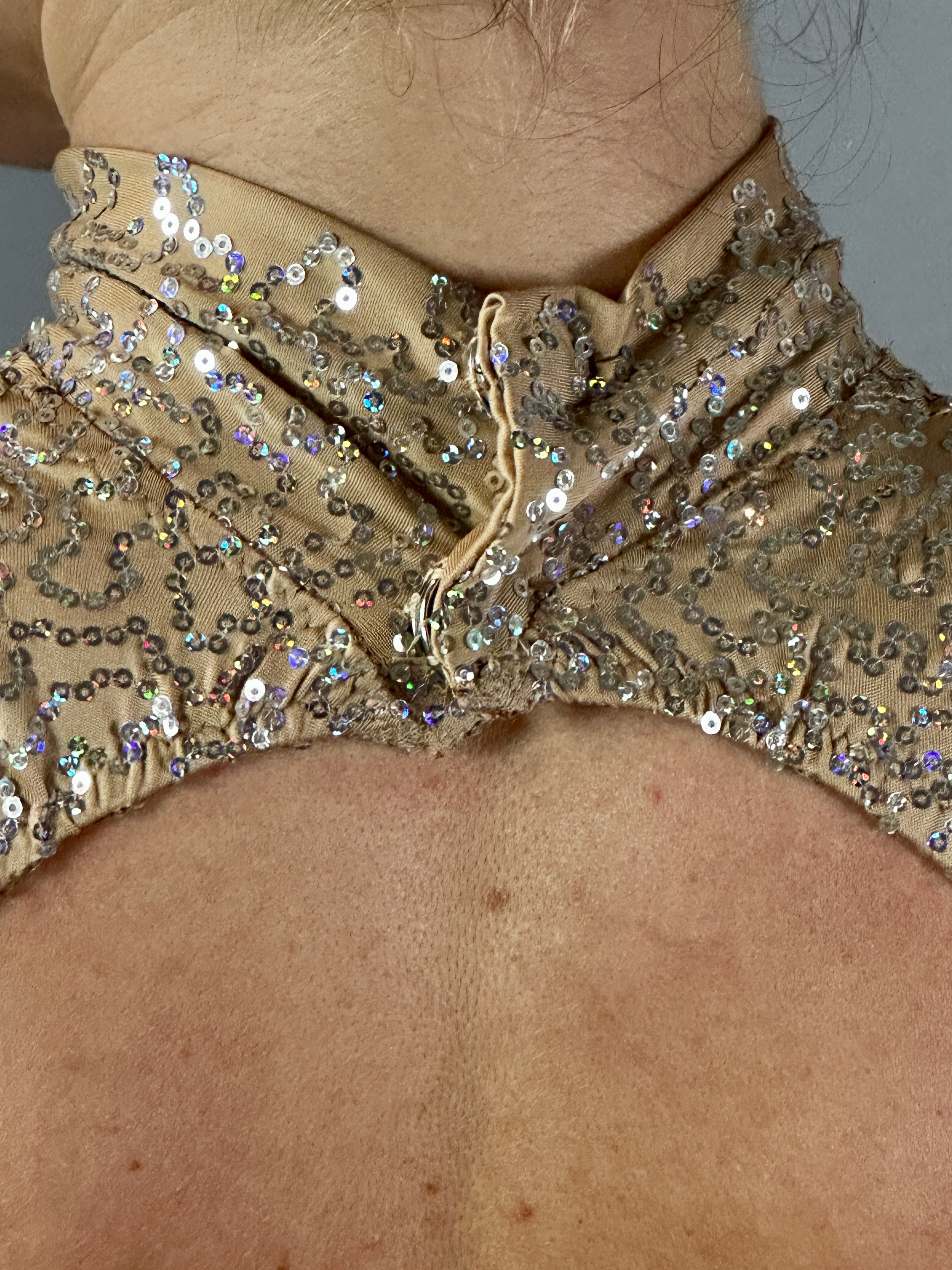 Close-up of the Champagne Fairy Sequin Catsuit featuring a turtleneck and open back, showcasing shimmering beige sequins and part of the wearer’s upper back.