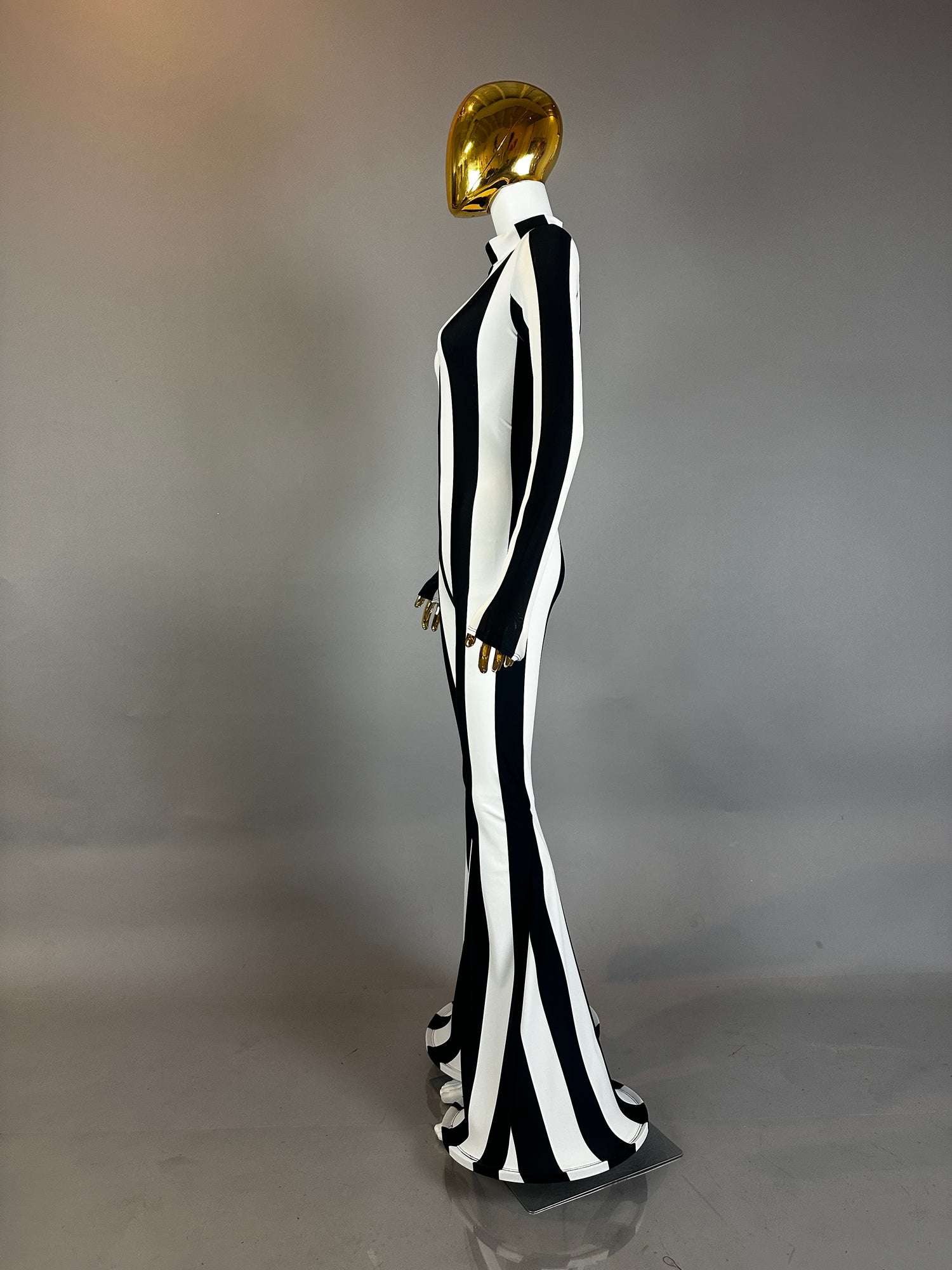 A mannequin in a gold mask wears the Rave White Striped Catsuit with bellbottom legs and long sleeves—a striking outfit for any festival performer.