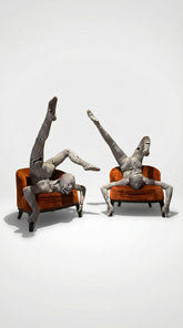 Two people in patterned bodysuits perform acrobatic poses on orange chairs against a plain background, showcasing the Alien Costume—futuristic fashion that&