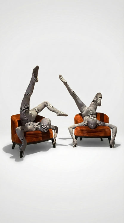 Two people in patterned bodysuits perform acrobatic poses on orange chairs against a plain background, showcasing the Alien Costume—futuristic fashion that&