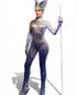 A person in the Futuristic Silver Robot Bodysuit—an exotic unisex costume for dance, alien cosplay & performance—wears a spiky 3D suit with a metallic finish and tall headpiece, holding a staff against a white background.