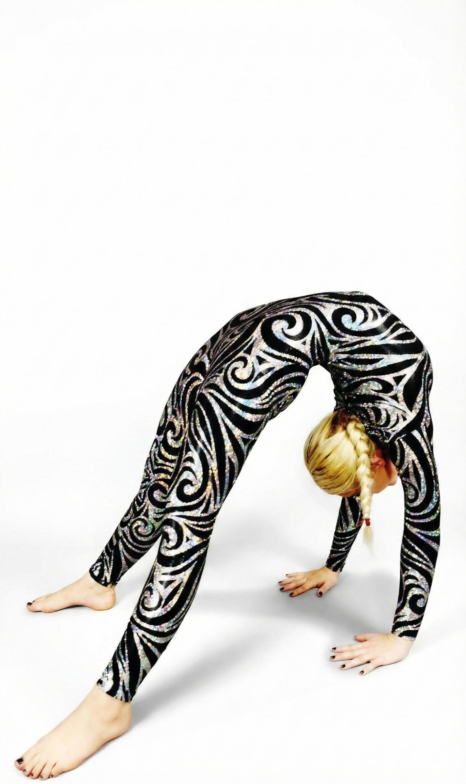A woman in a Jester Print Catsuit Full Body Costume, a colorful spandex jumpsuit with headpiece, gloves, and socks in UV glow fabric, does a backbend against a white background, evoking a vibrant dance performance.