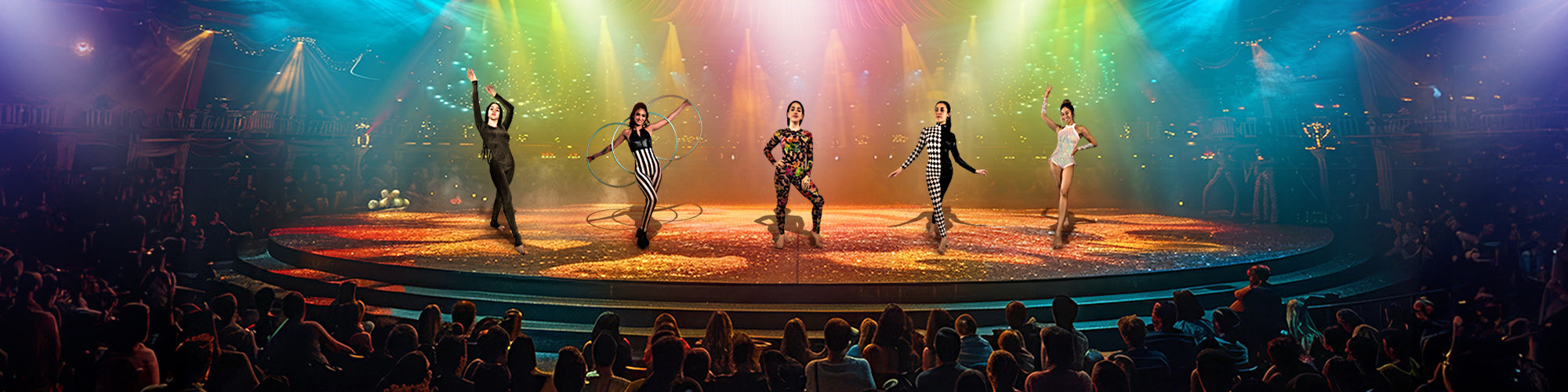 Five circus performers in colorful costumes perform on a round stage under vibrant, multicolored lights.