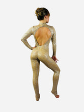 Woman stands barefoot in the Champagne Fairy Sequin Catsuit, featuring iridescent sequins, open back, turtleneck, and sleeves, while facing away on a white background.