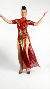 Woman wearing a Red And Gold Sequin Sheer Dress, sleeveless, with hand accessories, arms raised against a white background.