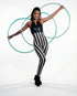 Woman poses with three hula hoops wearing a black and white striped spandex catsuit with a front zipper, a hologram halter top jumpsuit, and full body stretch performance wear against a white background.