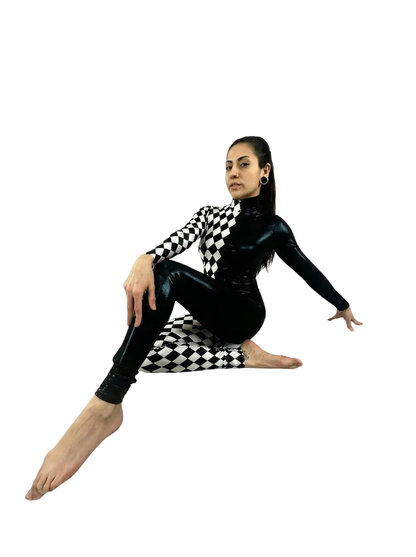 A woman wearing the Diamond and Black Jumpsuit with full sleeves and a turtleneck poses seated on the floor against a white background.