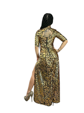 Woman wearing a Gold Mesh Dress with holographic geometric print, high slit, and open back—a sheer spandex party gown perfect for festivals and futuristic club wear—poses with her back to the camera.