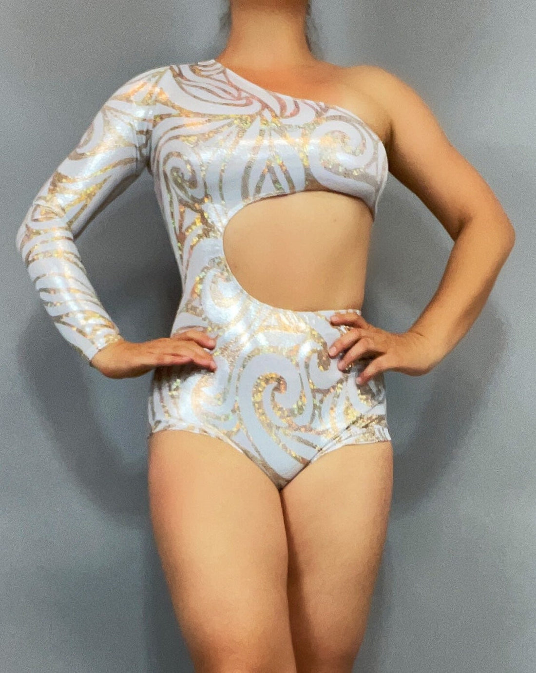 Person posing against a plain backdrop in a one-sleeve, cutout Leotard Costume for Gymnasts with a futuristic pattern, ideal as Circus Outfit, Exotic Dance Wear, or Pole Dance Costume.