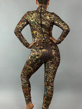 A person stands confidently, arms akimbo, in a colorful Alien Costume—an exotic dance wear Lycra jumpsuit for women or men. The abstract-patterned design hints at futuristic fashion against the stark gray background.