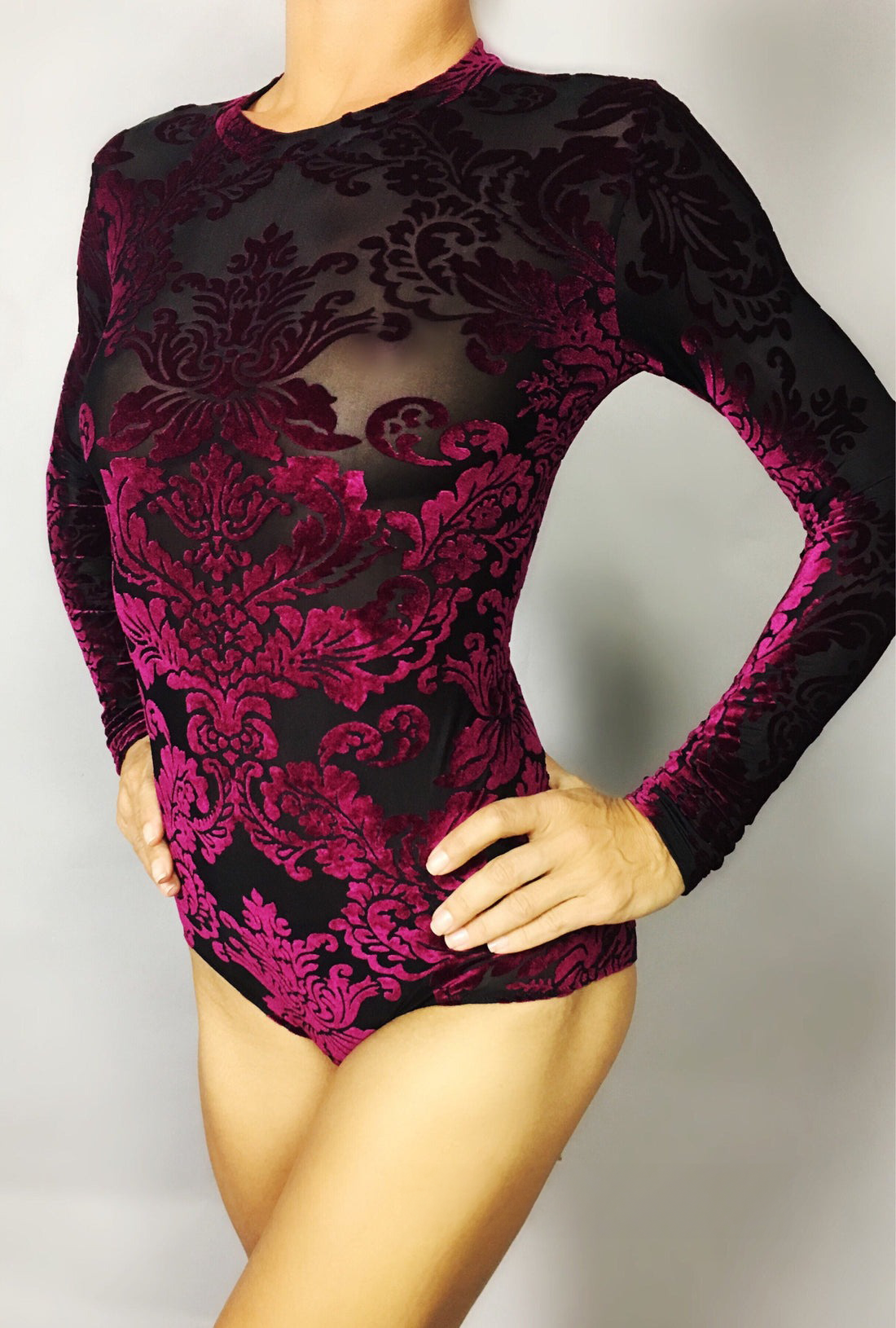 Model displays a custom sheer black Velvet Leotard with intricate pink velvet floral patterns, hands confidently on hips.