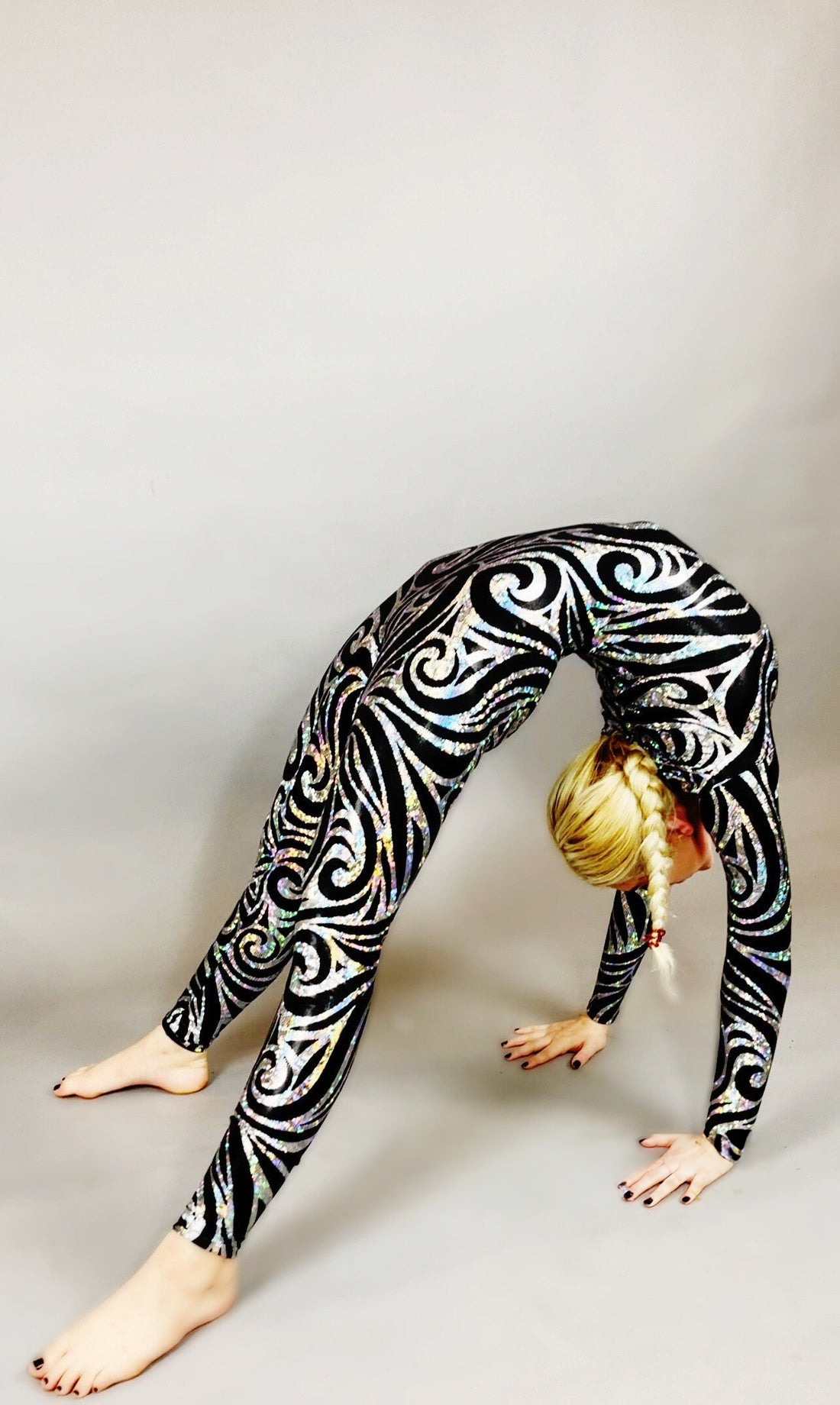 A person in a Gymnastic Jumpsuit, Exotic Dancewear spandex bodysuit gracefully performs a backbend on a gray floor.