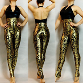 A model showcases a stylish unisex dancewear piece, the Black and Gold Sleeveless Catsuit. The design features a stunning snakeskin pattern, elegantly balancing flair with views from the front, side, and back.