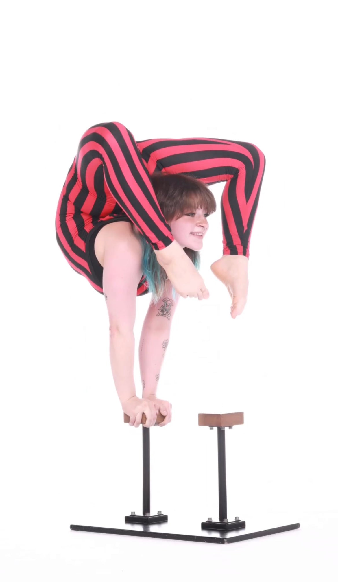 In a Red and Black Stripes Catsuit, Sleeveless Jumpsuit with Hand Accessories, an individual performs a graceful handstand, legs elegantly bent over the back.