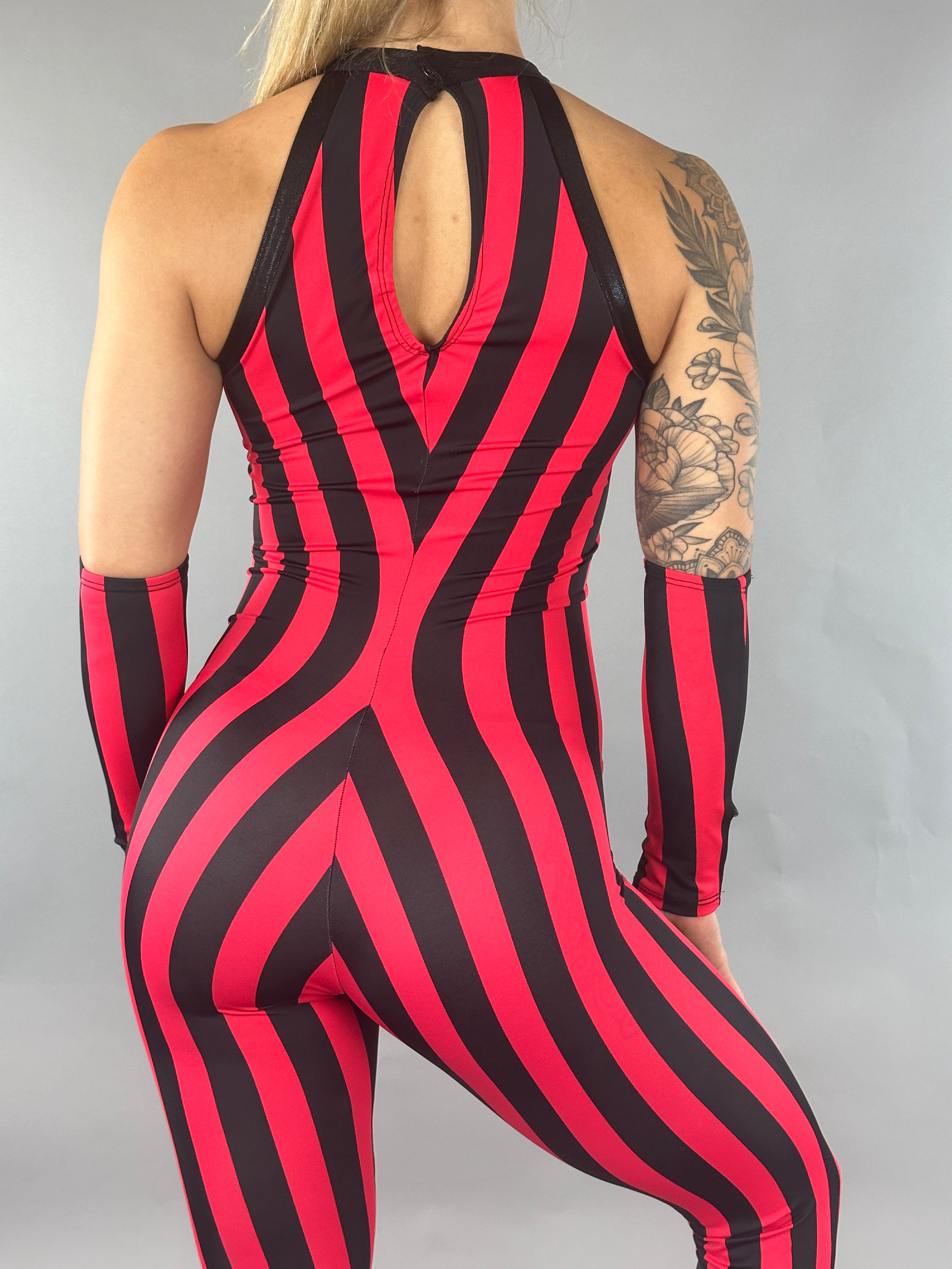 A person in a Red and Black Stripes Catsuit, complete with floral tattoos on their arm, faces away.
