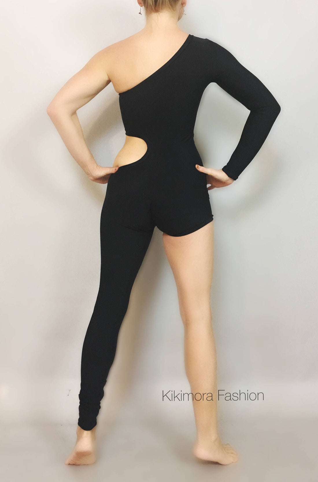 Person posing in the Unisex Isolated Black Catsuit, featuring an asymmetric design with cut-outs, one sleeve, and one full leg, set against a plain background.