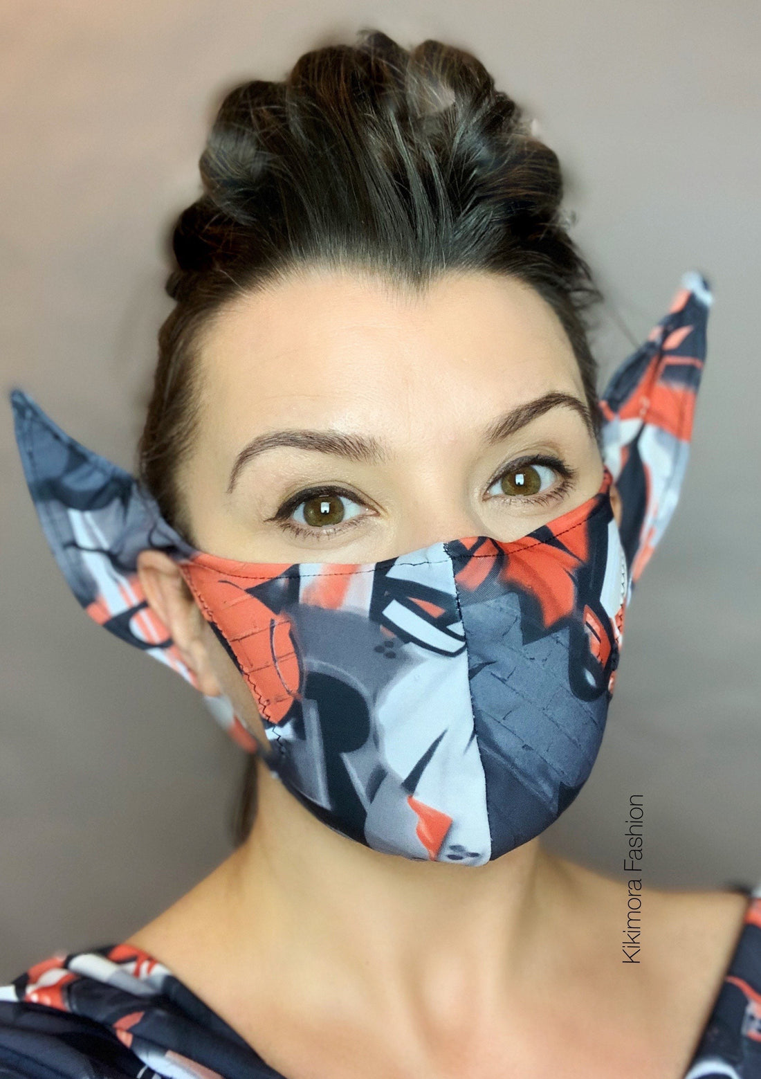 A woman models the Elf Ears Costume Face Mask—graffiti style with attached ears, inspired by Baby Yoda, featuring a HEPA filter—for a playful, sustainable look against a neutral background.